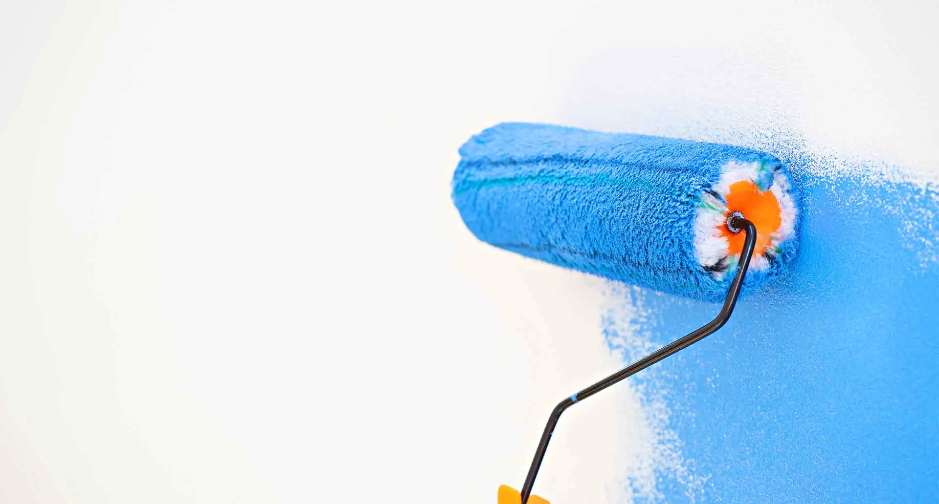 Professional painter applying blue paint with a roller brush for a smooth finish.